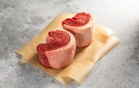 Two raw cuts of top sirloin picanha on parchment paper, ready for grilling.